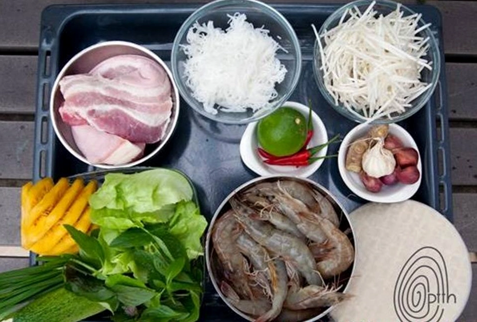 Bàn tay khéo léo đang cuốn bánh tráng với nhân tôm thịt rau bún