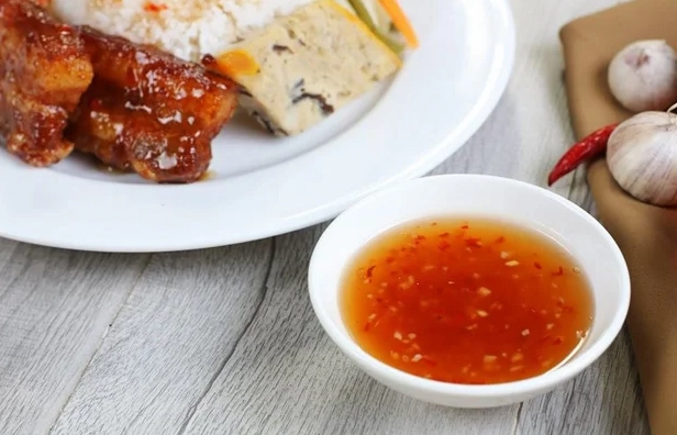 Chén nước mắm cơm tấm chua ngọt kẹo sền sệt rực rỡ sắc đỏ của ớt và tỏi băm