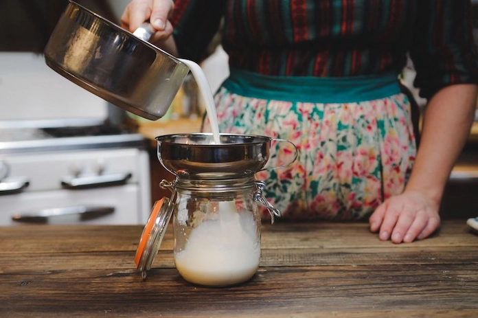 Chia hỗn hợp sữa đã pha men vào các hũ thủy tinh nhỏ
