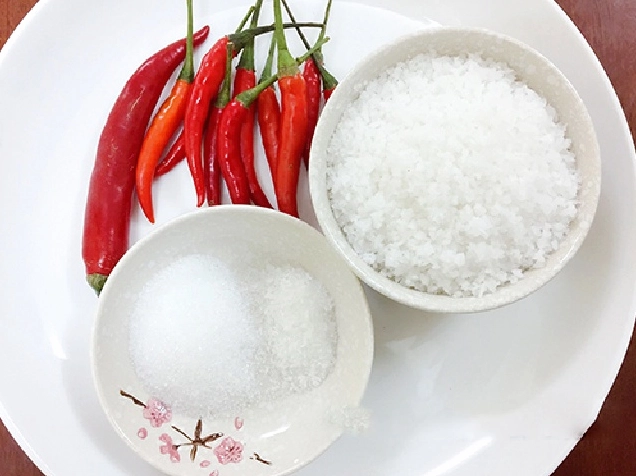 Dùng đũa đảo đều tay hỗn hợp muối và ớt đang được rang trên chiếc chảo chống dính
