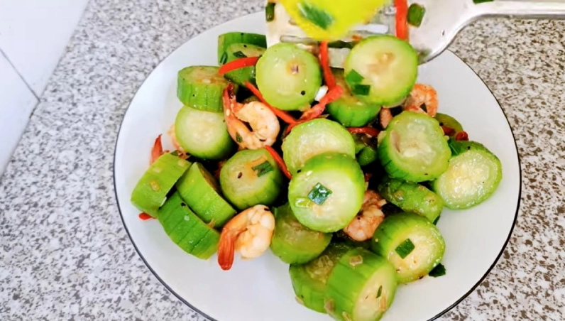 Gắp phần mướp xào tôm nóng hổi từ chảo ra đĩa để chuẩn bị thưởng thức