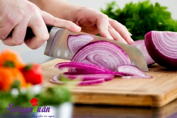 Hành tây được bóc vỏ và thái lát mỏng để trộn cùng nộm bắp cải