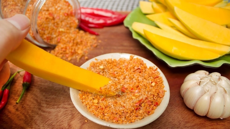 Hũ muối ớt rang đỏ au bắt mắt hấp dẫn bên cạnh đĩa hoa quả tươi ngon