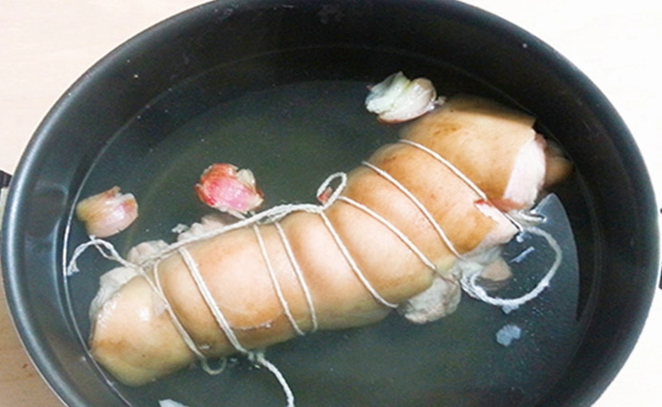 Luộc chân giò đã được cuộn chỉ trong nồi nước gia vị