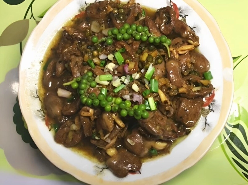 Món gà kho tiêu hoàn thiện được bày ra đĩa rắc thêm tiêu và hành lá