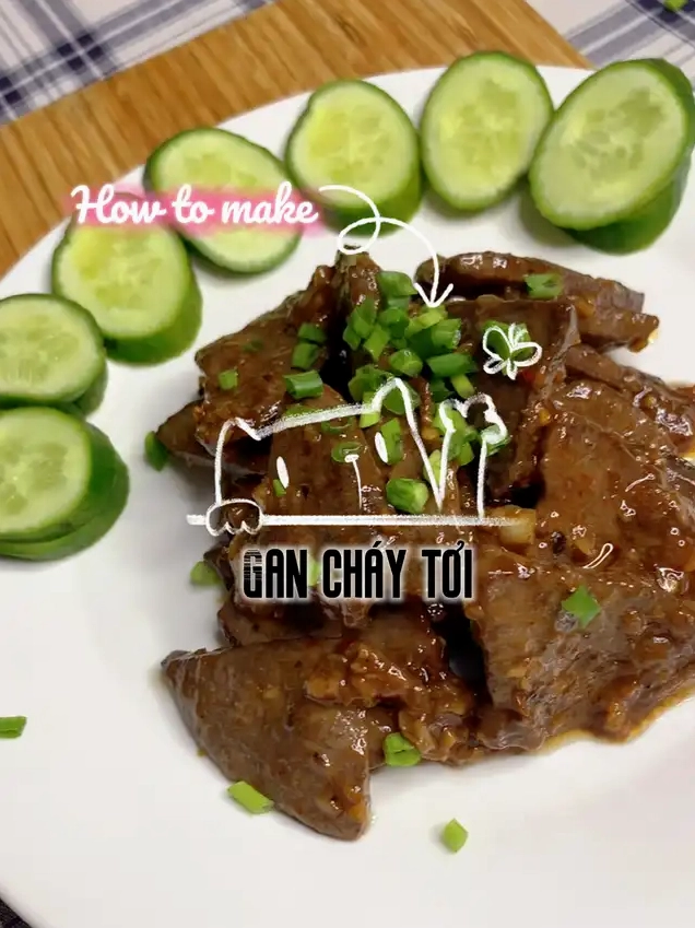 Một đĩa gan cháy tỏi đã hoàn thành được trang trí với dưa chuột thái lát và hành lá cắt nhỏ