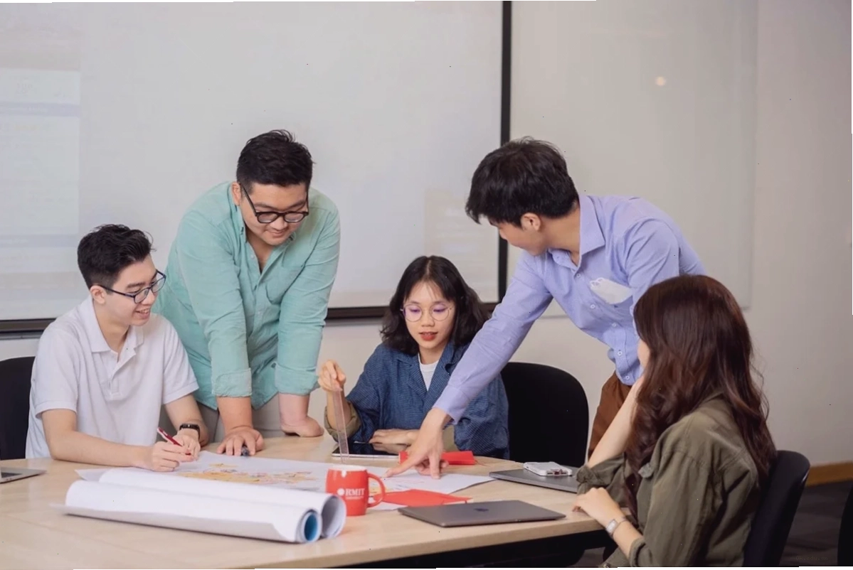 Một nhóm năm sinh viên vây quanh bàn học thảo luận bài học