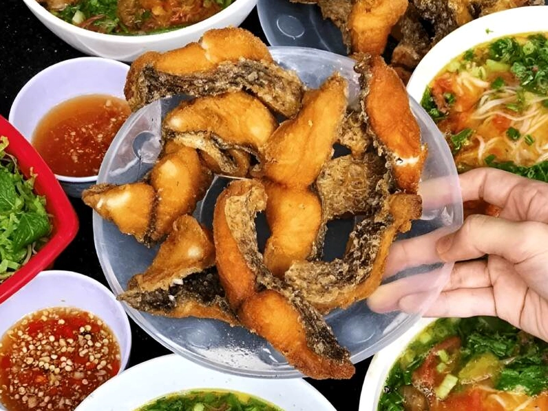 Những miếng cá rô phi đang được chiên vàng giòn trong chảo dầu sôi
