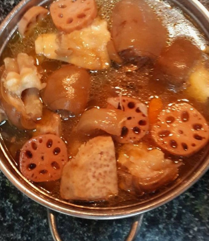 Nồi lẩu chân giò bò với đầy đủ đồ nhúng và rau sống tươi xanh