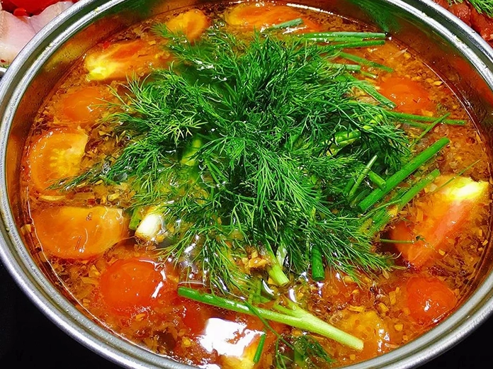 Nồi nước lẩu cá khoai đang sôi trên bếp màu sắc đỏ au bắt mắt