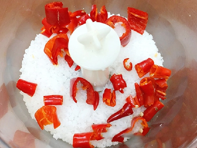 Ớt tươi màu đỏ rực rỡ đang được rửa sạch dưới vòi nước trong bồn rửa