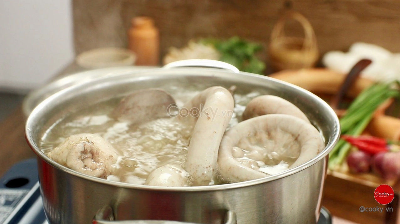 Quá trình luộc lòng heo trong nồi nước sôi sùng sục cùng gừng sả