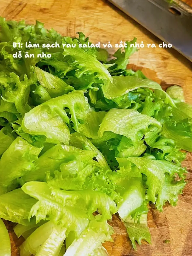 Rau xà lách xanh tươi đã rửa sạch cắt nhỏ đặt trên thớt gỗ minh họa bước làm sạch và thái rau