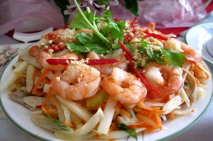 Trình bày đĩa gỏi bồn bồn tôm thịt ra đĩa rắc thêm đậu phộng và rau thơm