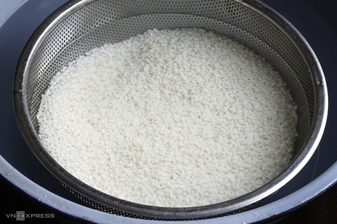 Vo gạo nếp nương cho tới khi nước trong để chuẩn bị đồ xôi